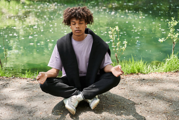 Calm man keeping eyes closed and meditating at the cozy forest or park - Foto, immagini