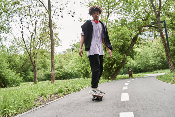 Man with curly hair practicing skateboarding while enjoying active rest at the urban road - Φωτογραφία, εικόνα