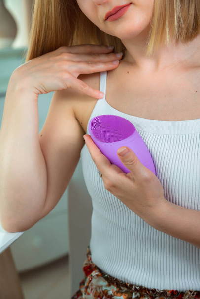 Gros plan de dispositif violet avec zone de boutons dans une main de jeune femme. Masseur silicone et nettoyant pour la peau. - Photo, image