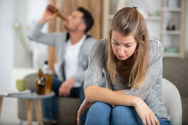 man pouring alcohol and woman sitting upset - Foto, Imagen
