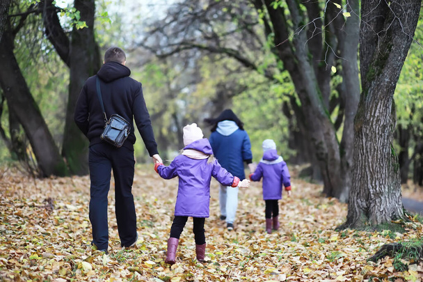 Παιδιά για βόλτα στο πάρκο του φθινοπώρου. Τα φύλλα πέφτουν στο πάρκο. Οικογένεια. Πτώση. Ευτυχία. - Φωτογραφία, εικόνα