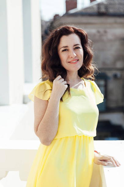 Portrait of a beautiful brunette woman in a yellow summer dress - Фото, изображение