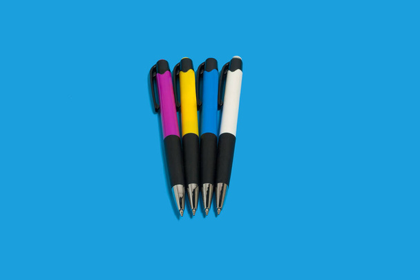 four colored pens on blue background. office accessories - Foto, afbeelding