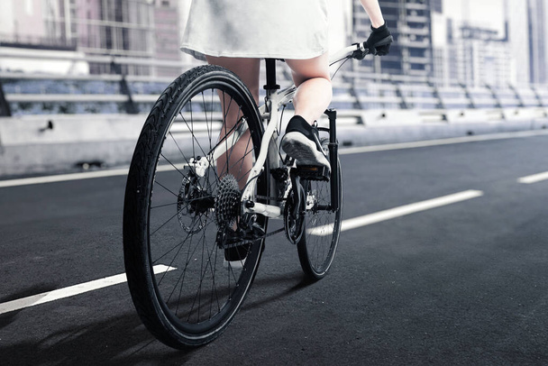 Rear view of a woman riding a bicycle on the street - Foto, imagen