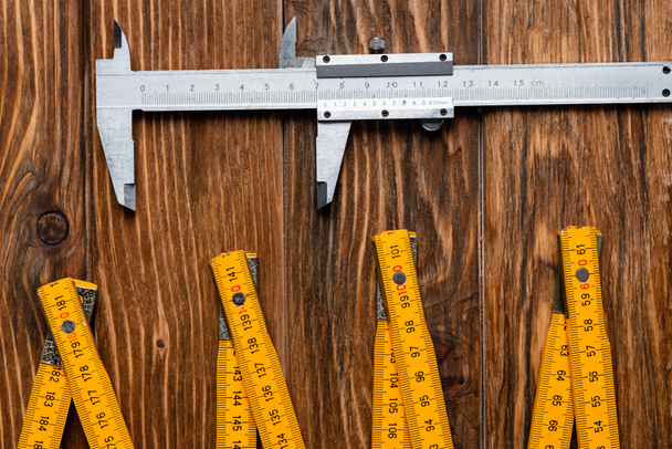 top view of folding ruler and calipers on wooden surface, labor day concept - Photo, Image