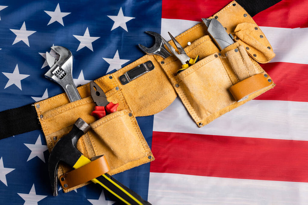 top view of leather tool belt with various tools on american flag, labor day concept - Photo, Image