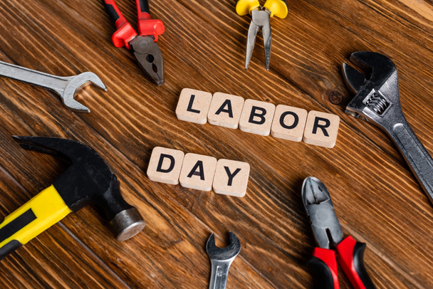 different tools and cubes with labor day lettering on wooden surface - Photo, Image