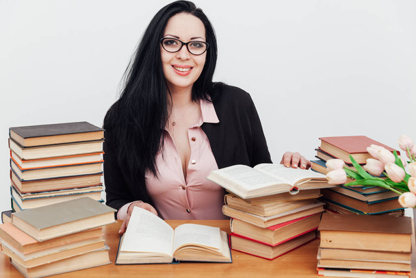 beautiful business woman in business suit at a table with stacks of educational books - Photo, Image
