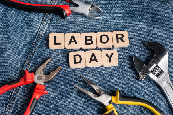 top view of cubes with labor day lettering near various tools on denim cloth - Photo, Image