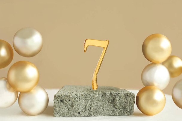 Nummer 7 op een betonnen podium en volumetrische gouden ballen op een beige achtergrond. Kopieerruimte. - Foto, afbeelding