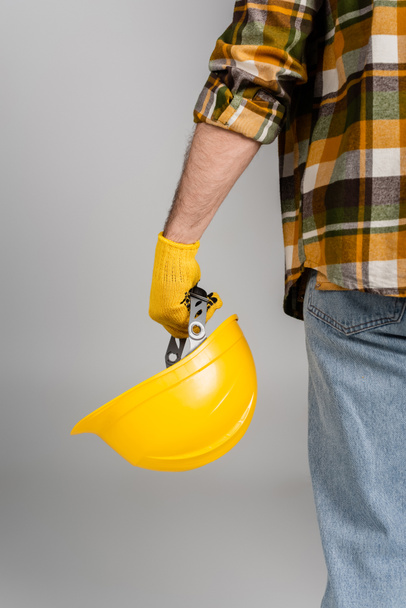 back view of cropped workman holding hardhat isolated on grey, labor day concept - Foto, Bild