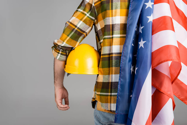 vista posterior del trabajador recortado con hardhat y bandera de EE.UU. aislado en gris, concepto del día del trabajo - Foto, Imagen