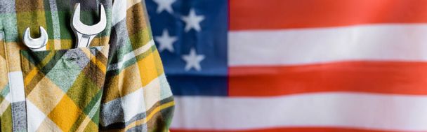 részleges kilátás munkás kockás ing csavarkulccsal a zsebében közel USA zászló elmosódott háttér, munkanap koncepció, banner - Fotó, kép