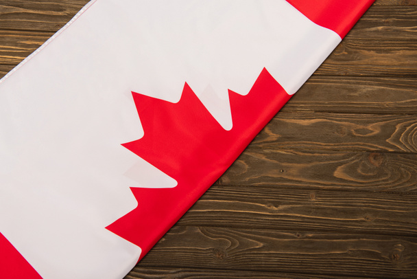 πάνω όψη καναδικής σημαίας με φύλλο σφενδάμου σε ξύλινη επιφάνεια  - Φωτογραφία, εικόνα