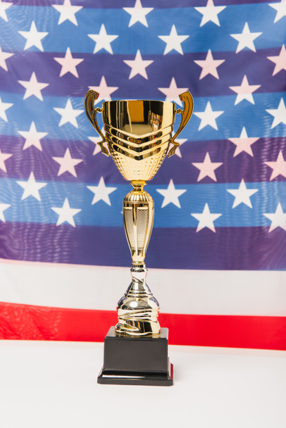 copa dorada con estrellas y rayas de bandera americana sobre fondo borroso - Foto, Imagen
