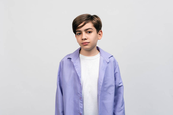 Retrato de um menino bonito 12-14 anos de idade olhando para a câmera sobre fundo cinza claro, vestido com roupas casuais. Estúdio tiro, isolado - Foto, Imagem
