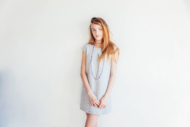 Chica adolescente de belleza. Retrato joven adolescente mujer en vestido gris sobre fondo blanco de la pared. Mujer europea - Foto, Imagen