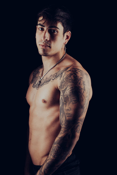 Hombre joven en forma con tatuajes en los brazos y el torso - Foto, imagen
