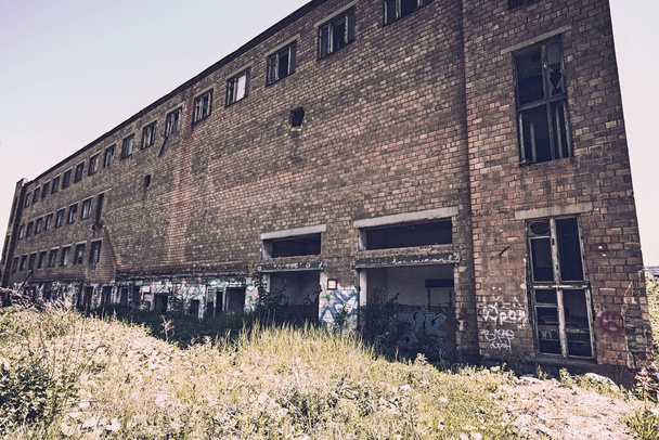 Stonowany wizerunek części opuszczonego budynku fabryki czerwonej cegły z rozbitym szkłem. Koncepcja zniszczenia. - Zdjęcie, obraz