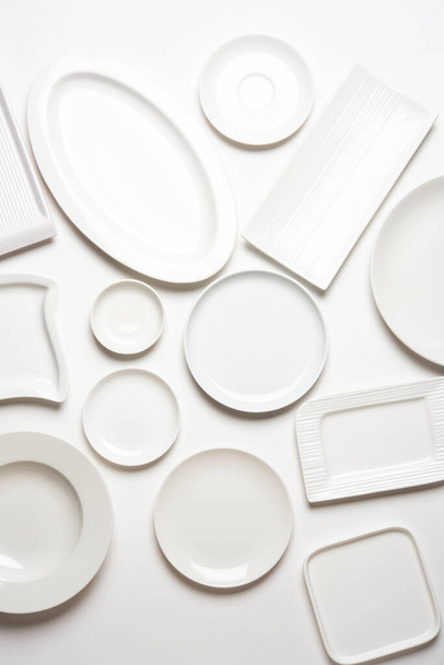 Empty white ceramic plates in group over white background, top view - Foto, immagini