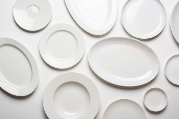 διαφορετικά σχήματα λευκά πιάτα που απομονώνονται σε λευκό φόντο, πάνω όψη - Φωτογραφία, εικόνα