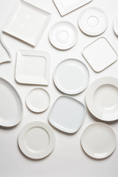 διαφορετικά σχήματα λευκά πιάτα που απομονώνονται σε λευκό φόντο, πάνω όψη - Φωτογραφία, εικόνα