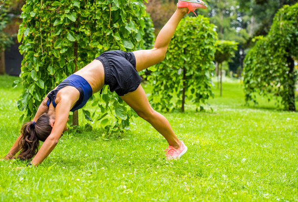 Schöne brünette weibliche Fitness-Mädchen, die draußen in einem grünen Stadtpark trainieren. Dame im Sporttop beim Joggen im Park. Gesunde Mädchen Lifestyle Hintergrund mit Kopierraum - Foto, Bild