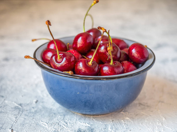 Blue cup with cherries on a light table close-up - Foto, immagini