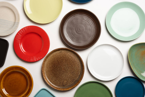 Placas de cerámica coloridas vacías en grupo sobre fondo blanco, vista superior - Foto, Imagen