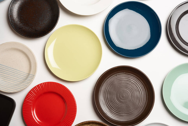 Empty colourful ceramic plates in group over white background, top view - Photo, Image