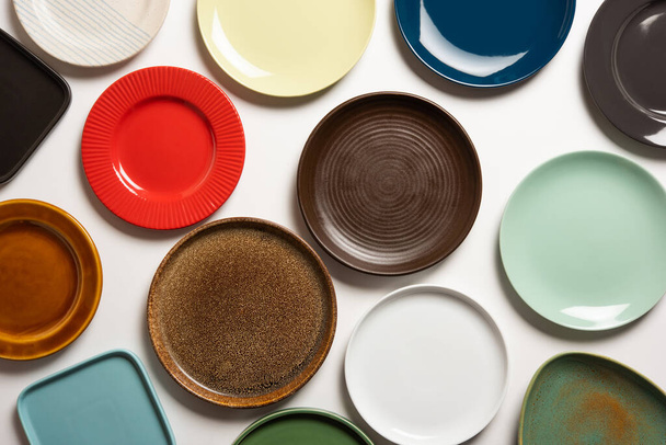 Placas de cerámica coloridas vacías en grupo sobre fondo blanco, vista superior - Foto, Imagen