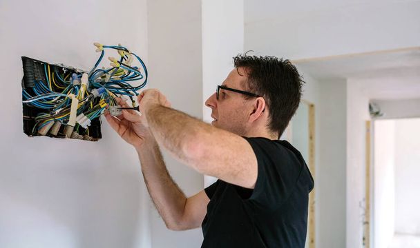 Elektriker arbeitet an der Elektroinstallation eines Hauses - Foto, Bild