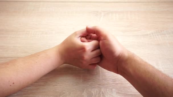 Ręka mężczyzny i kobiety robi puls kciuków na drewnianym stole - Materiał filmowy, wideo