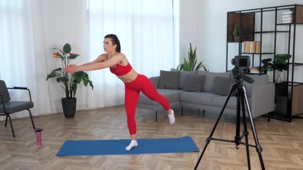 Entrenador de fitness mujer Fit haciendo ejercicio virabhadrasana 3 en esterilla de yoga en casa - Metraje, vídeo