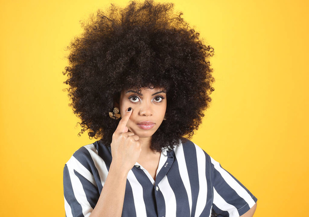 Afro woman, finger under eye, I watch you - Foto, afbeelding
