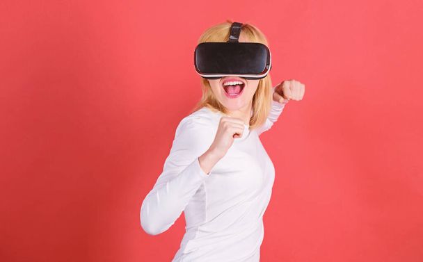 Portrait of young woman wearing VR goggles, experiencing virtual reality using 3d headset. Person with virtual reality helmet isolated on red background. VR poster. - Фото, изображение