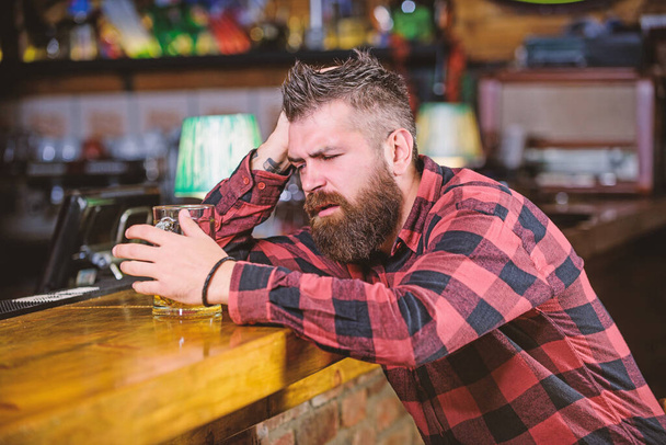 Bar is relaxing place have drink and relax. Man with beard spend leisure in dark bar. Brutal hipster bearded man sit at bar counter drink beer. Hipster relaxing at bar with beer. Order alcohol drink - Fotó, kép