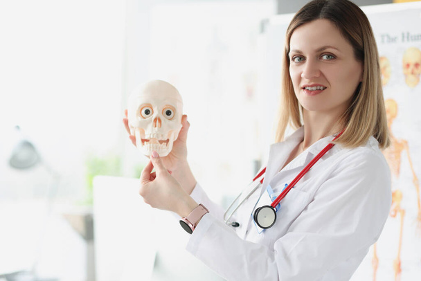 Female doctor teacher holding human skull closeup - Photo, Image