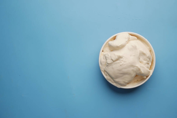 πάνω όψη της κρέμας γάλακτος σε δοχείο σε μπλε φόντο, - Φωτογραφία, εικόνα