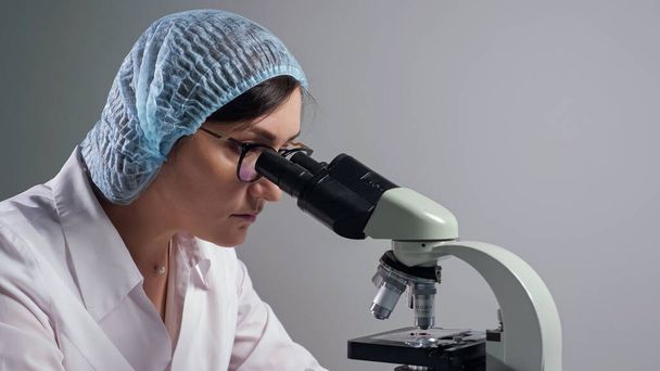 Вчений в окулярах дивиться на зразок через мікроскоп
 - Фото, зображення