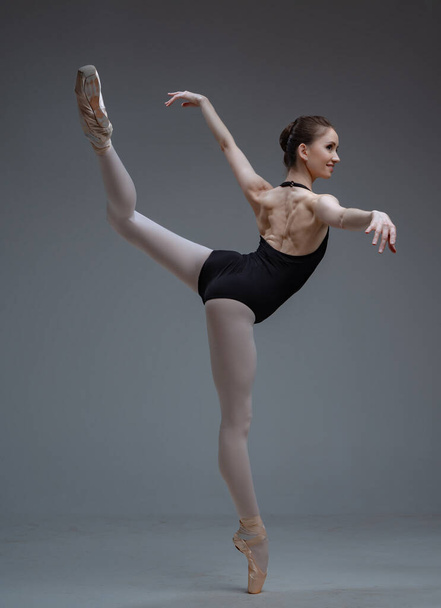 Graceful ballerina staying on one leg inside studio - Photo, Image