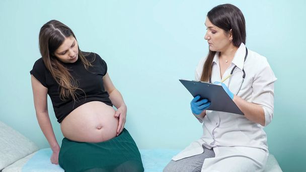 Vorsichtiger Arzt berührt Bauch einer Schwangeren in Klinik - Foto, Bild