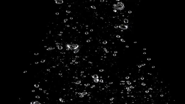 Bolle d'acqua gassata che schizzano sott'acqua e gocce d'acqua galleggianti su fondo nero. Filmati di film. rappresentano frizzante e rinfrescante di bevande gassate come cola o soda. Macro bolle. - Filmati, video