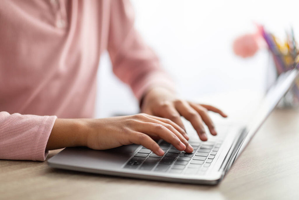 Concepto de personas y tecnología. Africano americano adolescente chica escribiendo en el teclado del ordenador portátil, estudiando en línea en casa, primer plano - Foto, imagen