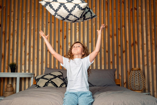 Nadšený mladý předškolní dívka padá na velké šedé posteli - Fotografie, Obrázek