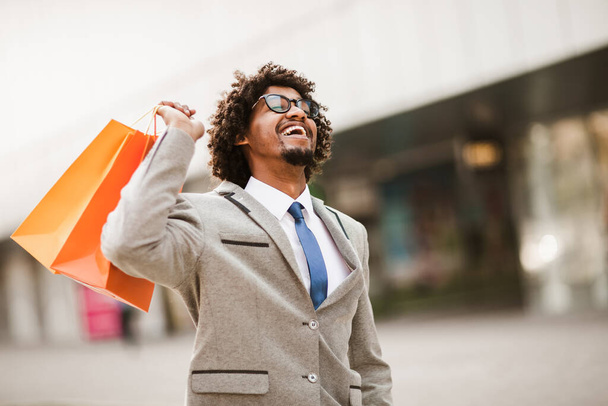 Man holding shopping bags looking very happy - Photo, Image