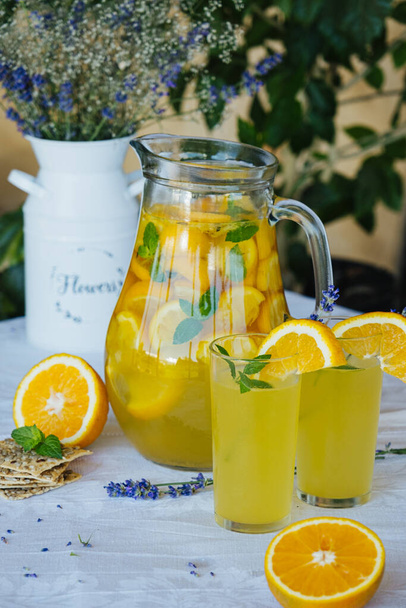 koude drank zomer limonade van sinaasappelen en munt met lavendel - Foto, afbeelding