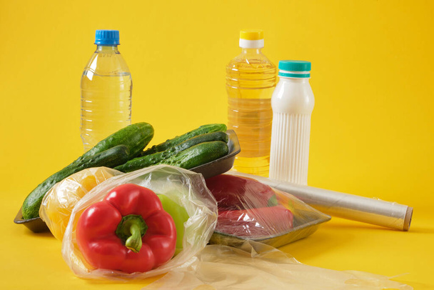 set of products in various plastic packaging, plastic environmental pollution concept, say no to plastic, yellow background copy space top view - Foto, immagini