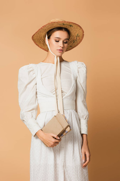 young woman in straw hat holding books on beige - Фото, изображение