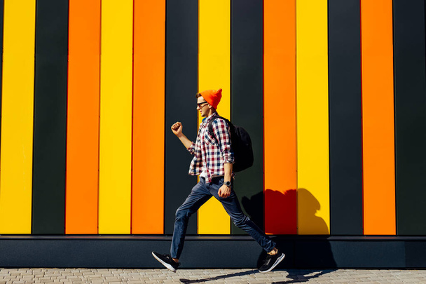 Photo of cheerful positive excited running jumping hipster man with briefcase striving for success against isolated urban multicolored wall background - 写真・画像